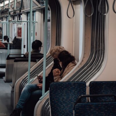 Photo by furkanfdemir Side view of friends in protective masks sharing mobile phone while riding in metro during pandemic